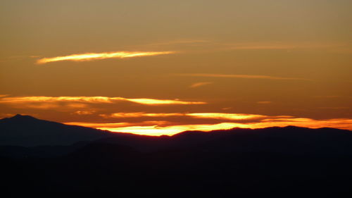 Scenic view of silhouette mountains against orange sky