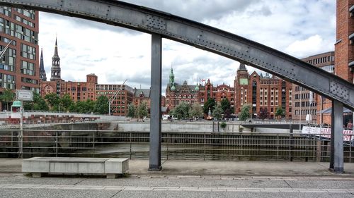Bridge over river by buildings in city against sky