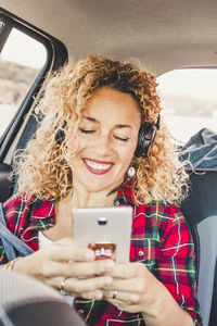 Young woman using phone while sitting in car