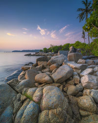 Rocks on beach against sky during sunset