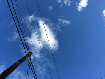 Low angle view of electricity pylon against blue sky