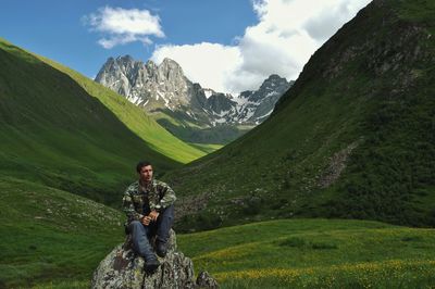 Man sitting on rock against mountains