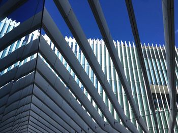 Low angle view of glass building against clear blue sky