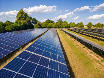 Solar panels with photovoltaic modules on an agricultural field with sunshine, drone perspective