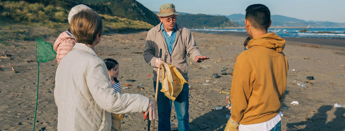 Grandfather guiding family while cleaning beach