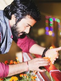 Side view of young man holding illuminated lighting equipment at night