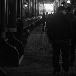 Rear view of people walking on train in city