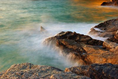 Scenic view of rocks in sea against rock formation