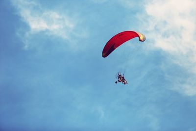 Low angle view of person paragliding against sky