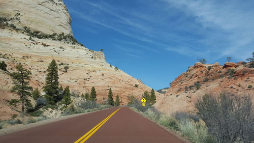 Empty country road against rocky mountains against sky