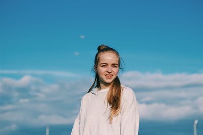 Portrait of young woman standing against sky