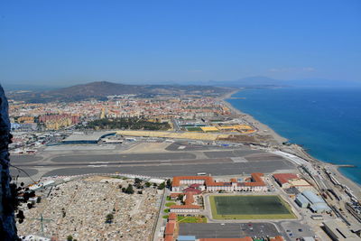 High angle view of buildings and sea against blue sky