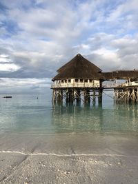 Built structure on beach by sea against sky