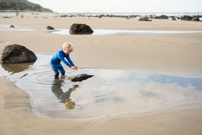 Young boy splashing water at new zealand beach