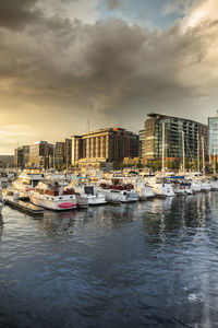 Boats moored in harbor against buildings in city