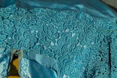 Close up of suare neckline of a cocktail dress in turquoise satin and macrame lace