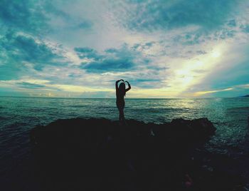 Silhouette man standing by sea against sky during sunset