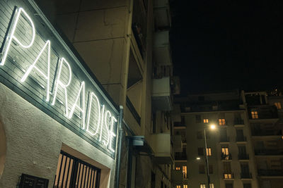 Low angle view of illuminated street light against building at night