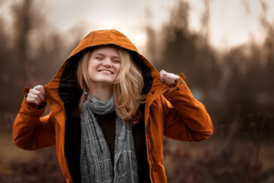 Portrait of young woman standing against blurred background