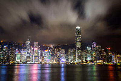 Illuminated modern buildings in city against sky at night