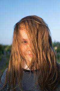 Portrait of girl with messy hair against blue sky