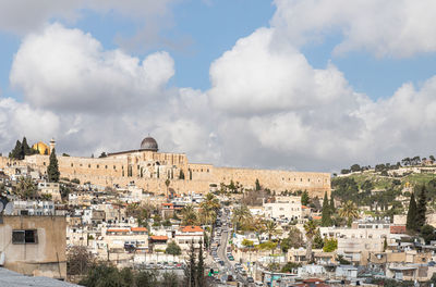 Buildings in town against cloudy sky