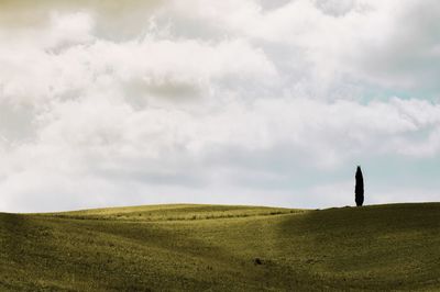 Rear view of man standing on landscape against cloudy sky