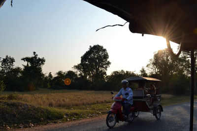 People cycling on road against sky