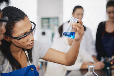 Young multi-ethnic chemistry students mixing solutions at laboratory in university