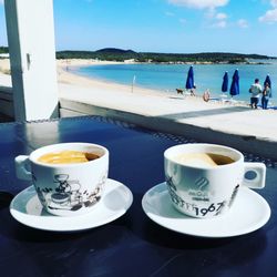 Close-up of coffee on table by sea against sky