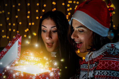 Portrait of young woman holding illuminated string lights