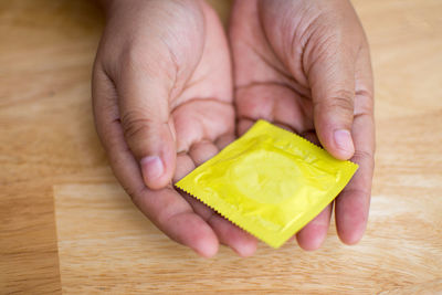 Close-up of man holding condom on table