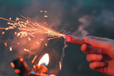 Cropped image of hand holding sparkler at night