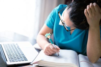 Midsection of woman reading book while sitting on table