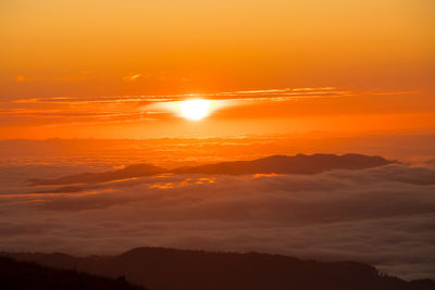 Scenic view of dramatic sky over silhouette landscape during sunset