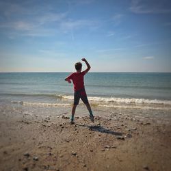 Full length of boy standing on beach against sky