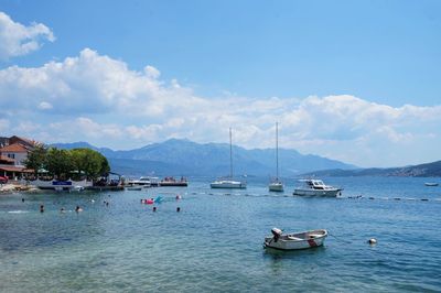 Sailboats moored in sea against sky