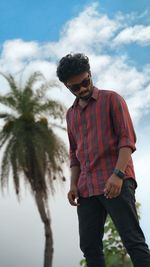 Young man wearing sunglasses standing against sky