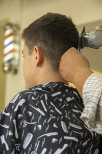 Cropped hand of barber cutting hair of boy