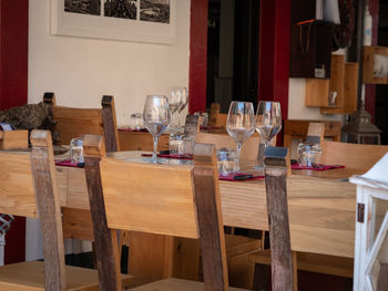 Empty wooden tables with crystal wine tasting glasses set for outdoor lunch 
