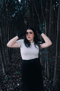 Portrait of young woman standing against trees