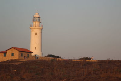 Lighthouse amidst buildings against sky