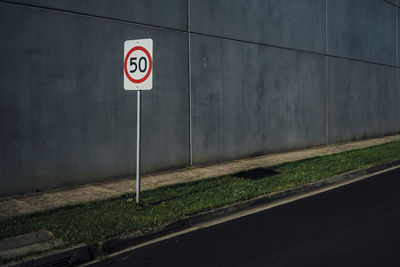 Information sign on grassy field by wall