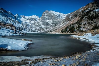 Scenic view of lake and mountains against blue sky