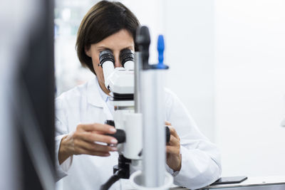 Female scientist using microscope at laboratory