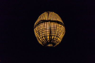 Low angle view of illuminated lamp against black background