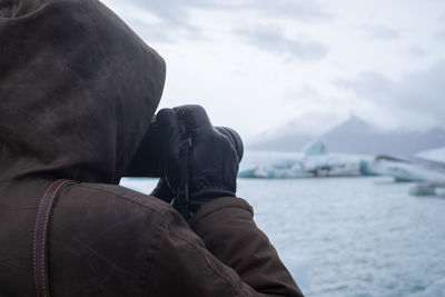 Rear view of man looking at sea against sky