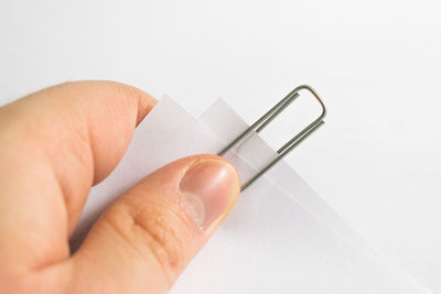 Close-up of hand holding paper over white background
