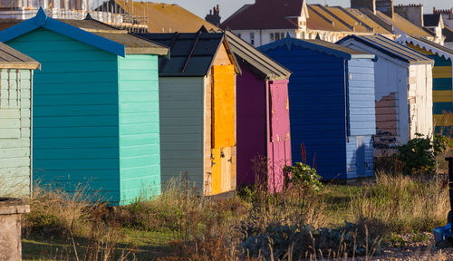 Multi colored houses on field by buildings against sky