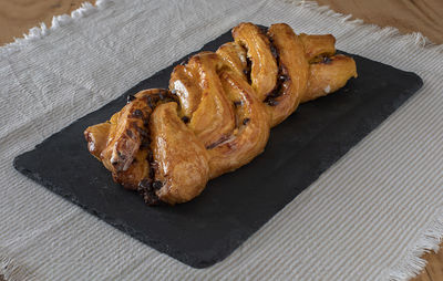 A whole sweet braid with chocolate on a slate dish.